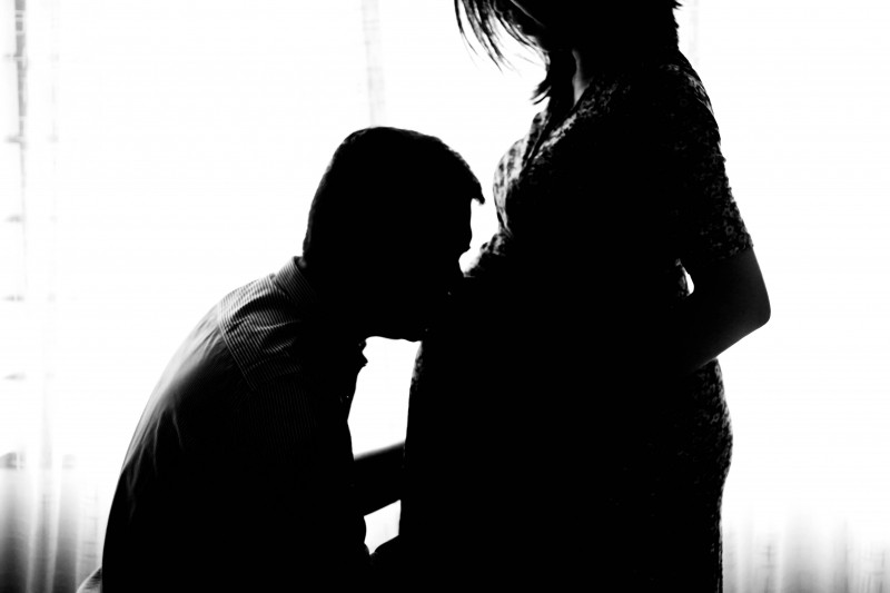 Homem beijando barriga de mulher grávida