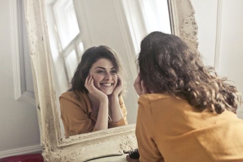 Mulher sorrindo em frente a um espelho